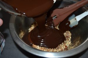 chocolat fondu verser sur les noisettes hachées et le pralin en grains