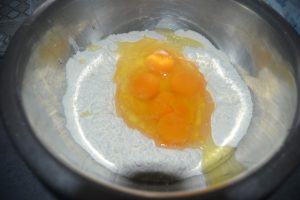 oeufs, beurre fondu, sucre et levure chimique dans le puits de farine